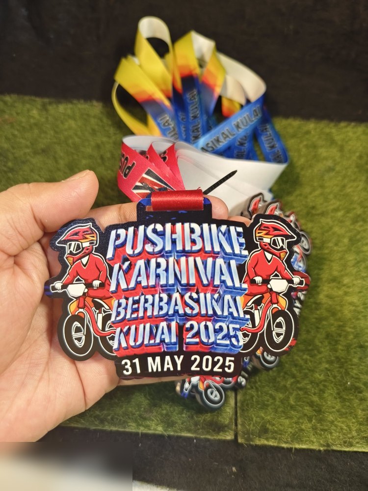 Medal Pushbike Karnival Kulai 2025 dlm kuantiti — tunjuk PELBAGAI WARNA LANYARD untuk satu design medal yang sama (kuning, biru, merah, putih). Contoh baik bila customer nak bezakan kategori umur guna