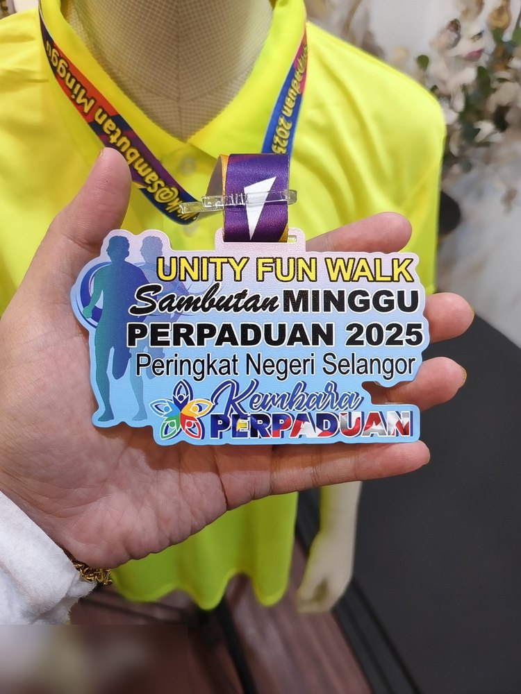 Medal Unity Fun Walk sempena Sambutan Minggu Perpaduan 2025 Peringkat Negeri Selangor. Bentuk custom mengikut susunan teks. Warna biru muda dengan silhouette dua orang berjalan dan logo 'Kembara Perpa